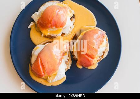 Toast con uova Benedict e salmone con salsa hollandaise su un piatto blu. Foto di alta qualità Foto Stock
