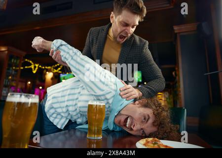 Amici ubriachi tifosi di football che lottano al bar dello sport a causa di litigi Foto Stock