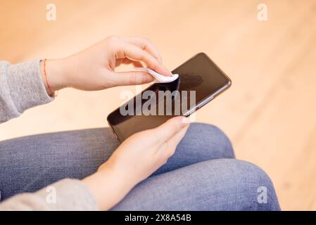 Processo di disinfezione del telefono. pulire lo schermo con una salvietta disinfettante mobile. Foto Stock