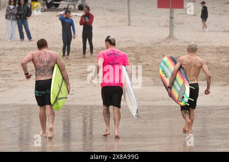 Surfisti che corrono fuori dal mare dopo aver partecipato alla gara di surf Sand Bandit Showdown al GT Western Great Western Beach di Newquay in Cornwal Foto Stock