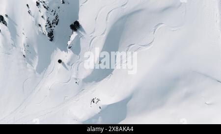 Vista aerea delle piste da sci e un freeskier su una pista innevata di montagna Foto Stock