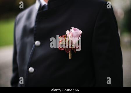 Primo piano del fiore all'occhiello di uno sposo con una rosa su un abito scuro. Foto Stock