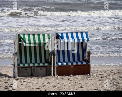 Due sedie a sdraio in piedi l'una accanto all'altra sulla spiaggia con il mare e le onde sullo sfondo, sedie da spiaggia bianche su una spiaggia del Mare del Nord contro una Foto Stock