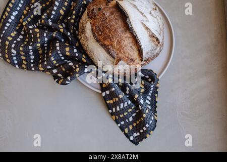 Pane rustico su un piatto con un panno a motivi geometrici Foto Stock