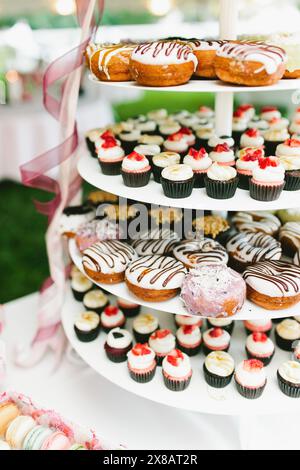 Ciambelle ghiacciate e cupcake alle fragole al tavolo dei dessert Foto Stock