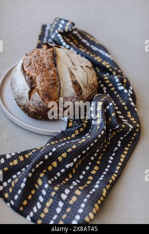 Pane rustico su un piatto con un panno a motivi geometrici Foto Stock