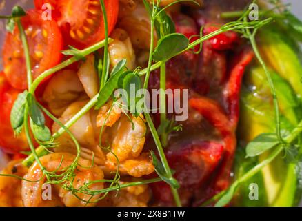 Gamberi grigliati, peperone rosso con avocado e pomodoro in un recipiente di plastica. Picchiettare la ciotola alla luce del sole. Cucina tradizionale asiatica. Cibo di strada da portare via. Foto Stock