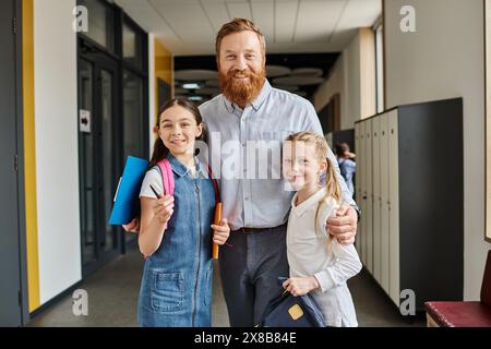 Un insegnante maschile si trova accanto a due ragazze in un ambiente vivace in classe, impegnato nell'insegnamento e nell'apprendimento. Foto Stock