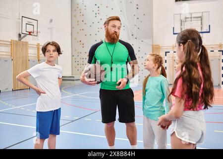 Un uomo che tiene un pallacanestro si trova su un campo da basket, pronto per una partita o una sessione di allenamento. Foto Stock