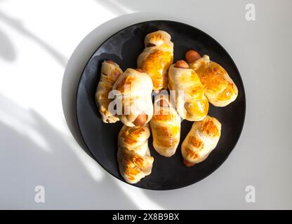 Salsicce nell'impasto su un piatto di ceramica sul tavolo. Foto Stock