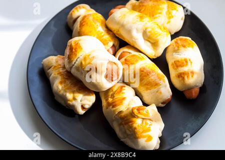 Salsicce nell'impasto su un piatto di ceramica sul tavolo. Foto Stock