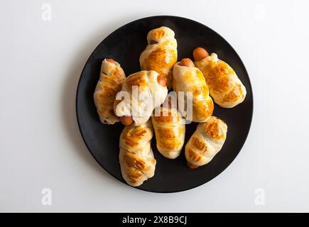 Salsicce nell'impasto su un piatto di ceramica sul tavolo. Foto Stock