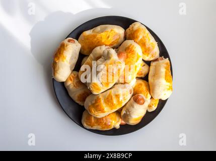 Salsicce nell'impasto su un piatto di ceramica sul tavolo. Foto Stock
