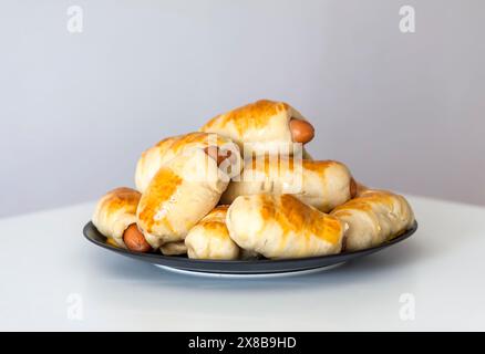 Salsicce nell'impasto su un piatto di ceramica sul tavolo. Foto Stock