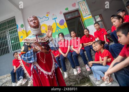 (240524) -- CHONGQING, 24 maggio 2024 (Xinhua) -- gli studenti di una scuola elementare ascoltano le dimostrazioni dell'artista dell'Opera di Yangxi Chen Yongxia a Youyang Tujia e Miao Autonomous County, Chongqing, 17 maggio 2024. Nel villaggio Qingquan di Tonggu Township a Youyang, c'è un gruppo di artisti d'opera composto da agricoltori locali di età media di quasi 70 anni, che eseguono l'antica opera di Yangxi sui cortili e sulle dighe come palco, e tra risaie, montagne e foreste come sfondo nel villaggio a circa 1.000 metri sul livello del mare circondato da montagne e acque Foto Stock