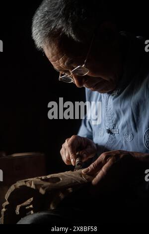 (240524) -- CHONGQING, 24 maggio 2024 (Xinhua) -- l'artista dell'Opera di Yangxi Chen Yongxia scolpisce una maschera dell'Opera di Yangxi nel villaggio di Qingquan del Tonggu Township, Youyang Tujia e Miao Autonomous County, Chongqing, 16 maggio 2024. Nel villaggio Qingquan di Tonggu Township a Youyang, c'è un gruppo di artisti d'opera composto da agricoltori locali di età media di quasi 70 anni, che eseguono l'antica opera di Yangxi sui cortili e sulle dighe come palco, e tra risaie, montagne e foreste come sfondo nel villaggio a circa 1.000 metri sul livello del mare circondato da mountai Foto Stock