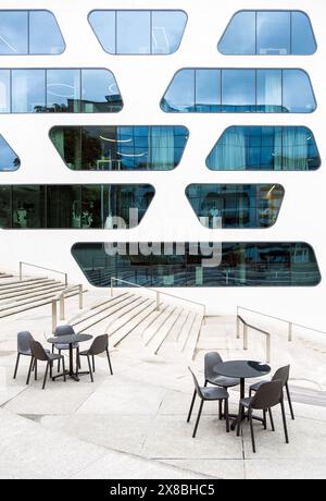 Tavoli da caffe' vuoti di fronte ad un moderno edificio di uffici, con facciata dall'architettura contemporanea Foto Stock