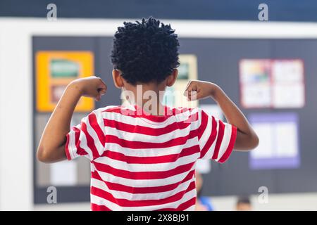 A scuola, giovane afroamericano che mostra braccia forti in classe Foto Stock