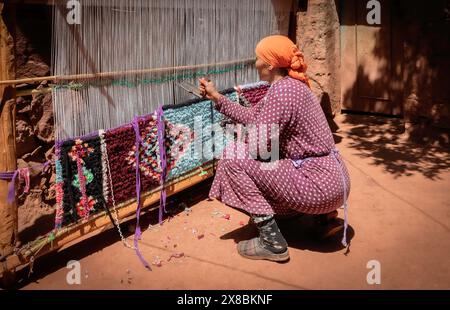 Una donna berbera marocchina che tesseva un tappeto all'aperto su un telaio a mano, a casa, in un villaggio rurale nelle montagne dell'alto Atlante, nella valle di Ourika, in Marocco Foto Stock