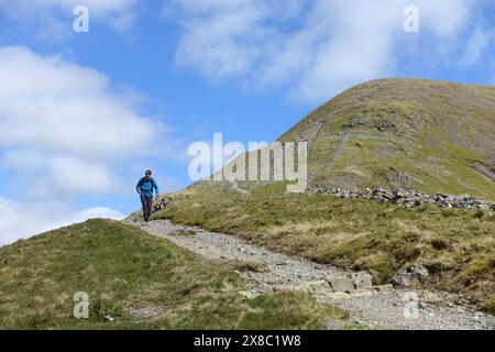 Lone Man (escursionista) camminando lungo il Wainwright 'Fairfield' fino a Grisedale Hause e Grisedale Tarn nel Lake District National Park, Cumbria, Inghilterra, Regno Unito. Foto Stock