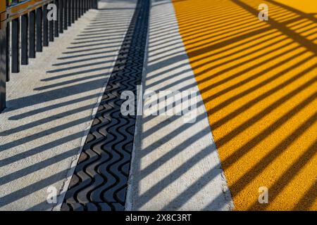 Immagine nel tardo pomeriggio di uno scarico di trincee in metallo ornamentale in cemento con motivo ombra da una recinzione ornamentale adiacente. Foto Stock