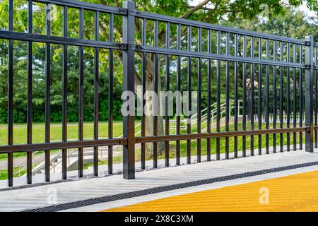 Immagine nel tardo pomeriggio di uno scarico di trincee in metallo ornamentale in cemento con motivo ombra da una recinzione ornamentale adiacente. Foto Stock