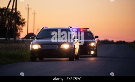 Il conducente che sta superando la velocità viene fermato dalla polizia pattugliando la macchina . Il colpo largo delle due vetture si fermò in una strada che attraversava un campo aperto. Il driver ubriaco viene catturato da ufficiali professionisti Foto Stock