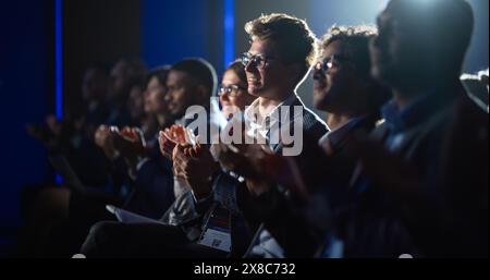 Giovane uomo seduto in un pubblico affollato a una conferenza scientifica. Il partecipante applaude e applaude dopo un discorso chiave di ispirazione. Auditorium con Young Successful Specialist. Foto Stock