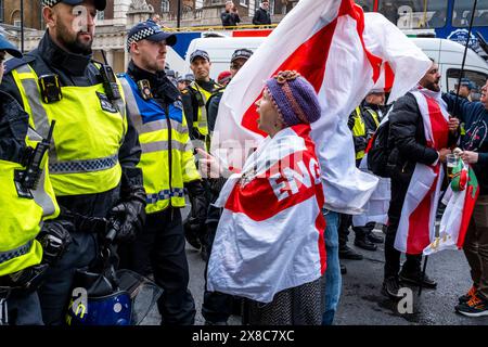 Una donna avvolta nella bandiera della Croce di San Giorgio grida agli agenti di polizia dopo il conflitto alle celebrazioni del giorno di San Giorgio, Londra, Regno Unito. Foto Stock