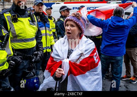 Una donna avvolta nella bandiera della Croce di San Giorgio grida agli agenti di polizia dopo il conflitto alle celebrazioni del giorno di San Giorgio, Londra, Regno Unito. Foto Stock