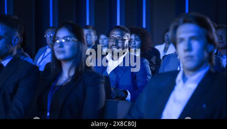 Uomo nero seduto in un pubblico affollato a una conferenza d'affari. Corporate Delegate si concentra su un discorso, ascoltando una presentazione per l'imprenditoria ispiratrice sui mercati in via di sviluppo. Foto Stock