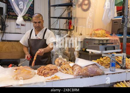 Mercato di città del Messico; Un macellaio che taglia il pollo al suo banco di carne, mercato alimentare al coperto di San Juan, città del Messico, Messico Foto Stock