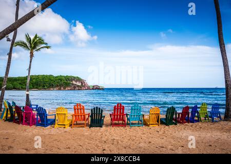 Colorato semicerchio di sedie Adirondack adagiato sulla riva di Bolongo Beach. Foto Stock