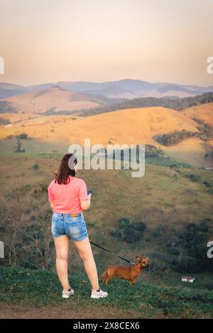 Una donna brasiliana cammina con il suo cane nella campagna di Santa Branca, in Brasile, durante il tramonto. Foto Stock