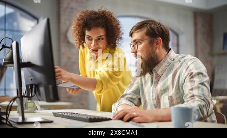 Ritratto di due colleghi creativi che collaborano e indicano il computer in Modern Office. Biracial Female Manager consulta male Projects Manager, They Brainstorm sul progetto. Foto Stock