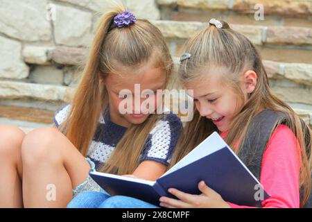 allegra ragazze delle scuole elementari che seguono un taccuino che studiano sedute sulle scale Foto Stock