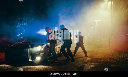 Poliziotto maschio che costringe un civile conforme all'Hood of Police Car. Sospettata di detenzione femminile a Gun Point. Agente che spinge violentemente Man contro la macchina. Scandaloso caso di brutalità della polizia. Foto Stock