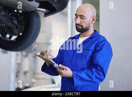 Uomo, meccanico e redazione con appunti per l'assistenza, l'elenco di controllo o il rapporto sulla riparazione generale in officina. Uomo o ingegnere meccanico che prende Foto Stock