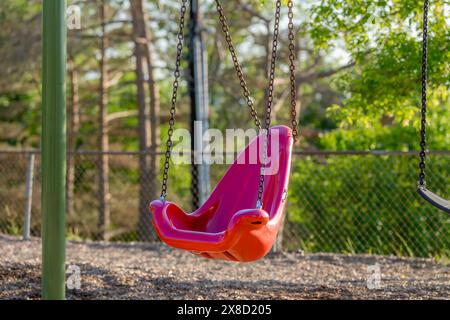 Altalena, sedia, in una tipica scuola elementare, parco municipale, parco giochi con superficie di sicurezza in fibra di legno. Foto Stock