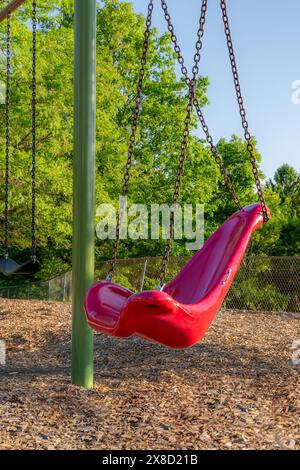 Altalena, sedia, in una tipica scuola elementare, parco municipale, parco giochi con superficie di sicurezza in fibra di legno. Foto Stock