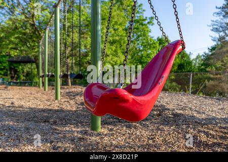 Altalena, sedia, in una tipica scuola elementare, parco municipale, parco giochi con superficie di sicurezza in fibra di legno. Foto Stock