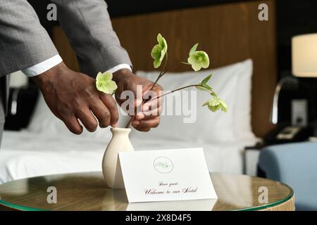 Primo piano della nota di benvenuto in un hotel di lusso con mani maschili che organizzano un arredo floreale copia spazio Foto Stock