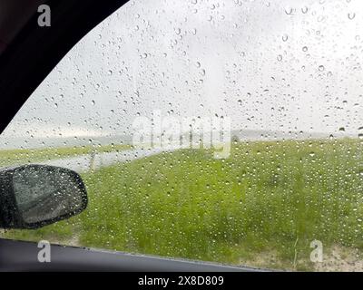 Finestrino laterale di un'auto con gocce di pioggia durante una tempesta Foto Stock