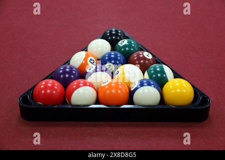 Set di palline da biliardo in un triangolo su un tavolo rosso Foto Stock