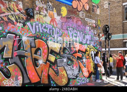 L'area colorata e vibrante di Brick Lane, il giorno del mercato della domenica, al sole dell'inizio dell'estate, a est di Londra, Regno Unito Foto Stock