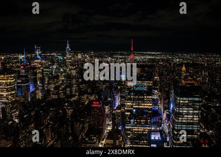 Skyline notturno di Manhattan da una prospettiva audace dall'alto. Giganti torreggianti perforano le nuvole, offrendo un punto panoramico unico per il viaggio. Foto Stock