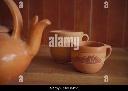 Bollitore e tazze in terracotta su sfondo di un tavolo in legno. Foto Stock