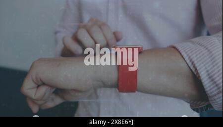 Partner maschile caucasico che regola lo smartwatch rosso al polso, indossando una camicia rosa chiaro Foto Stock