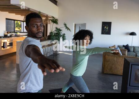 Una coppia diversa che pratica yoga a casa Foto Stock