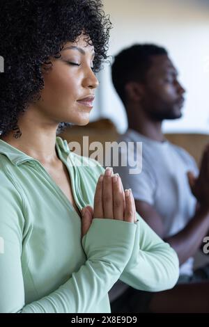 Una coppia diversificata che meditava a casa, entrambi con capelli ricci Foto Stock